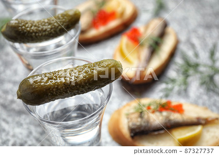 Cold Russian vodka with pickles on grey table, closeup 87327737