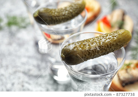 Cold Russian vodka with pickles on grey table, closeup 87327738