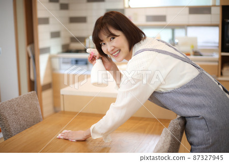 A woman wiping a table 87327945