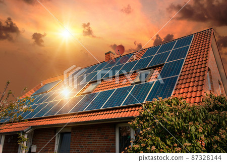 Photo collage of solar panels, photovoltaics on the red roof of a house and a beautiful sky with the setting sun. Alternative electricity source. Concept of sustainable resources 87328144
