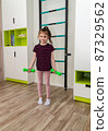 A little girl goes in for sports in her room. 87329562