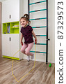 A little girl goes in for sports in her room. 87329573