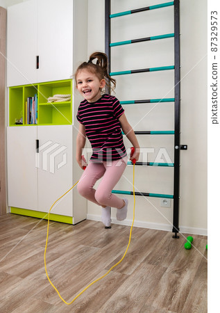 A little girl goes in for sports in her room. 87329573