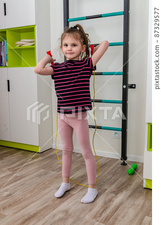A little girl goes in for sports in her room. A little girl goes in for sports in her room. 87329577