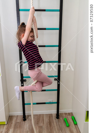 A little girl goes in for sports in her room. 87329580