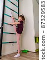 A little girl goes in for sports in her room. 87329583