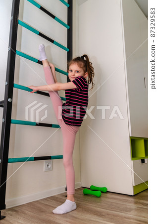 A little girl goes in for sports in her room. 87329583