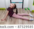 A little girl goes in for sports in her room. 87329585