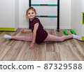 A little girl goes in for sports in her room. 87329588