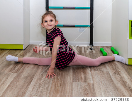 A little girl goes in for sports in her room. A little girl goes in for sports in her room. 87329588