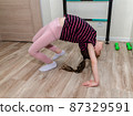 A little girl goes in for sports in her room. 87329591