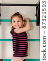 A little girl goes in for sports in her room. 87329593