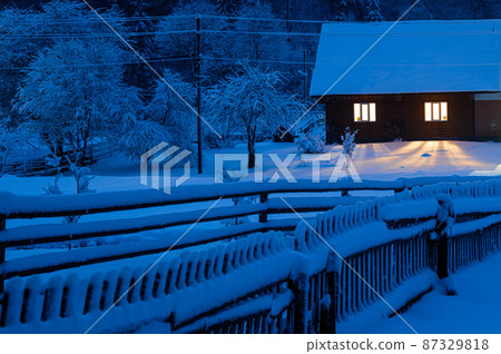 old house covered with snow in the evening old house covered with snow in the evening 87329818