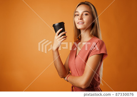 Attractive young woman standing and drinking hot drink 87330076