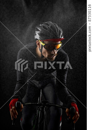 male cyclist riding road bicycle on black background 87330116