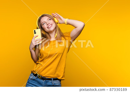 Girl in headphones with phone in studio Girl in headphones with phone in studio 87330189