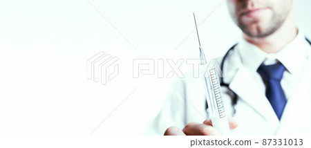 Syringe needle medical injection. Selective focus, doctor hand in blue gloves holding syringe with needle. Hospital white doctor gown, stethoscope. Syringe with flu vaccine with copy space. 87331013