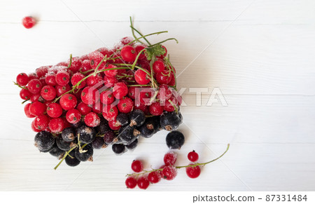 Frozen red and black currants in on a light background . The concept of preparing products for use in the future. Frozen red and black currants in on a light background . The concept of preparing products for use in the future. 87331484
