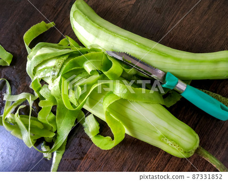Two peeled green bottle gourd placed on a wooden table 87331852