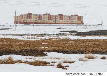 View of the snowy tundra and colorful buildings during the snowfall 87332009