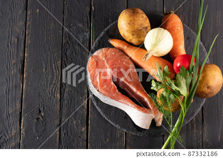 Red fish steak and vegetables on the table. Products for cooking. Selected vegetables and fish. Copy space. Red fish steak and vegetables on the table. Products for cooking. Selected vegetables and fish. Copy space. 87332186