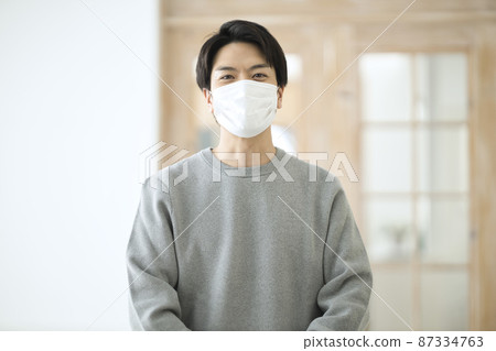 A man in his thirties wearing a mask in the room A man in his thirties wearing a mask in the room 87334763