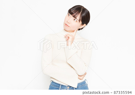 A casually dressed woman standing in front of a white background A casually dressed woman standing in front of a white background 87335594