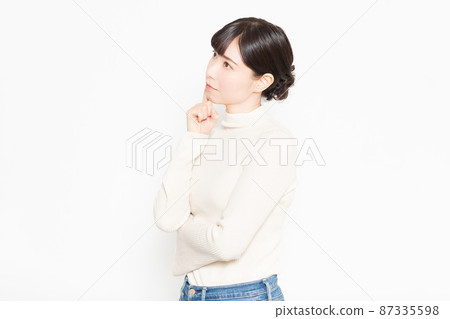 A casually dressed woman standing in front of a white background 87335598