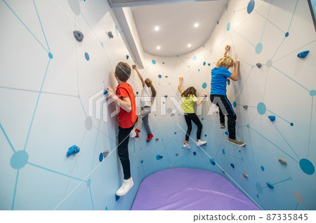Focused kids hanging on climbing wall Focused kids hanging on climbing wall 87335845