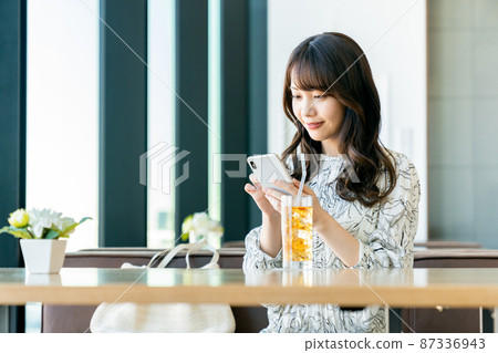 A young woman watching a smartphone at a cafe 87336943