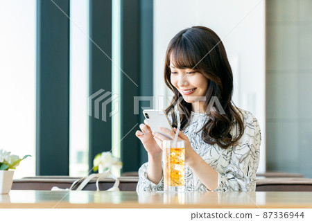 A young woman watching a smartphone at a cafe 87336944