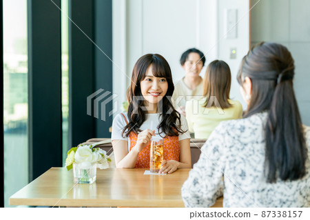 A young woman gathering with friends at a cafe 87338157
