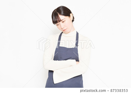 A woman wearing an apron standing in front of a white background 87338353