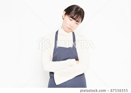 A woman wearing an apron standing in front of a white background 87338355