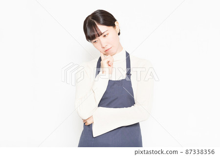 A woman wearing an apron standing in front of a white background A woman wearing an apron standing in front of a white background 87338356
