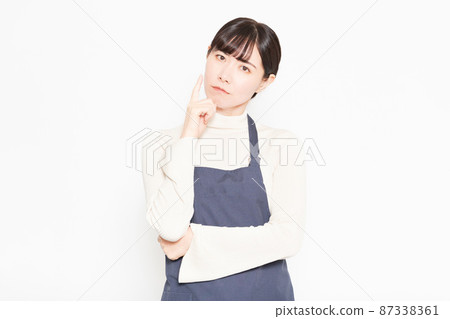 A woman wearing an apron standing in front of a white background 87338361