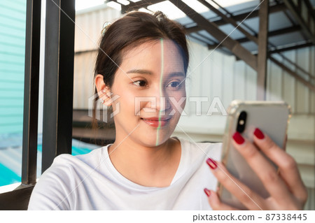 Asian woman is checking her personal data. Scanning her face by smart phone to unlock it. Concept of data protection. 87338445