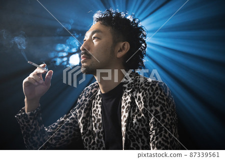Bearded man in a leopard print jacket smoking a cigarette 87339561