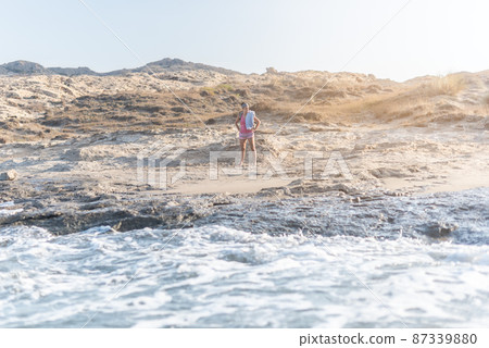 Woman on sandy beach near foamy sea Woman on sandy beach near foamy sea 87339880