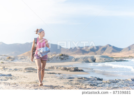 Relaxed woman walking on sandy beach near sea Relaxed woman walking on sandy beach near sea 87339881