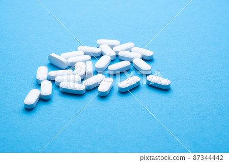 White pills on a blue background close-up. White pills on a blue background close-up. 87344442