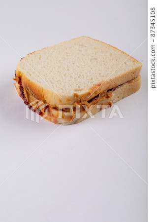 Close-up of peanut butter and jelly sandwich on white background with copy space Close-up of peanut butter and jelly sandwich on white background with copy space 87345108