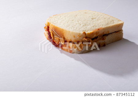 Close-up of peanut butter and jelly sandwich on white background with blank space 87345112