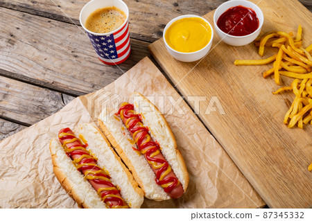 High angle view of hot dogs with french fries and sauces by drink on table 87345332