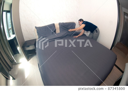 An Asian female maid making bed in hotel room. Housekeeper Making Bed.  87345800