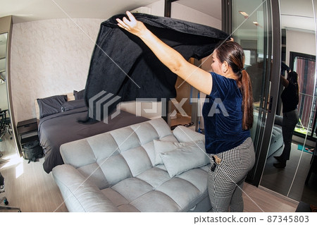 An Asian female maid making bed in hotel room. Housekeeper Making Bed. An Asian female maid making bed in hotel room. Housekeeper Making Bed. 87345803