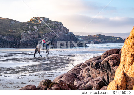 Horse riding at Cloughglass bay and beach by Burtonport in County Donegal - Ireland 87346000