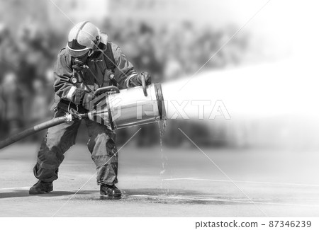 Firefighters while extinguishing the fire with a special fire extinguishing equipment. Firefighters while extinguishing the fire with a special fire extinguishing equipment. 87346239