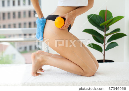 Cellulite problem concept, young woman holding orange near her leg 87346966