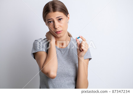 Sick woman suffering from sore neck on gray background 87347234